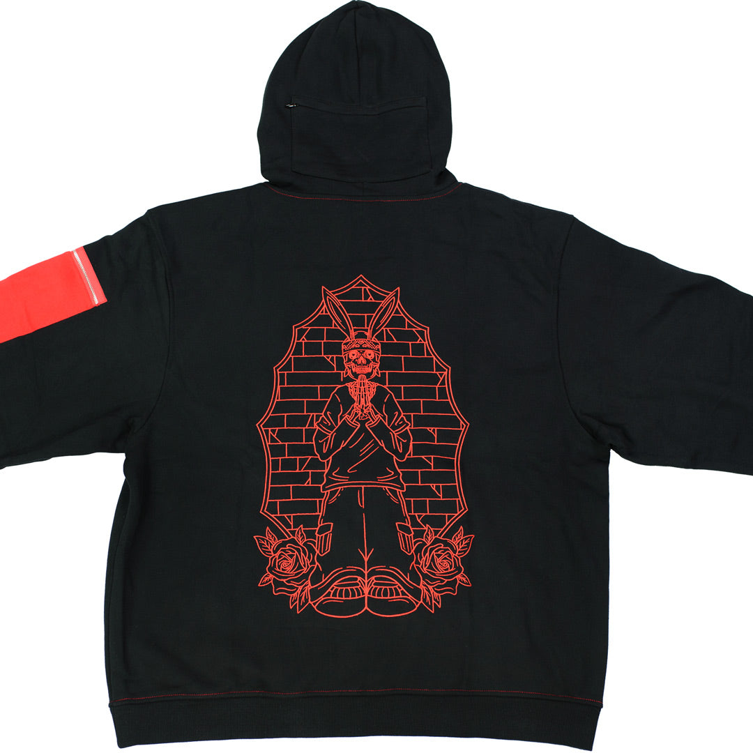 back view of red and black hoodie with red embroidered praying rabbit design. there is a zipper pocket behind the hood
