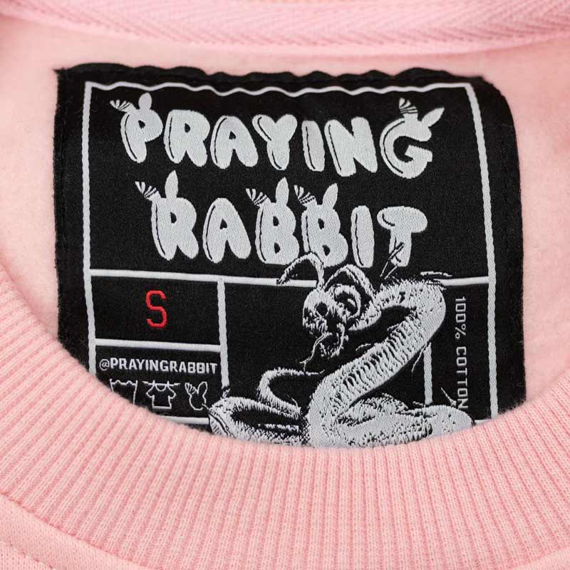 praying rabbit woven label with rabbit skeleton snake design on pink crew neck sweater