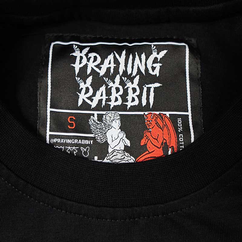 inside woven label that reads praying rabbit and has both an angel and demon on it.