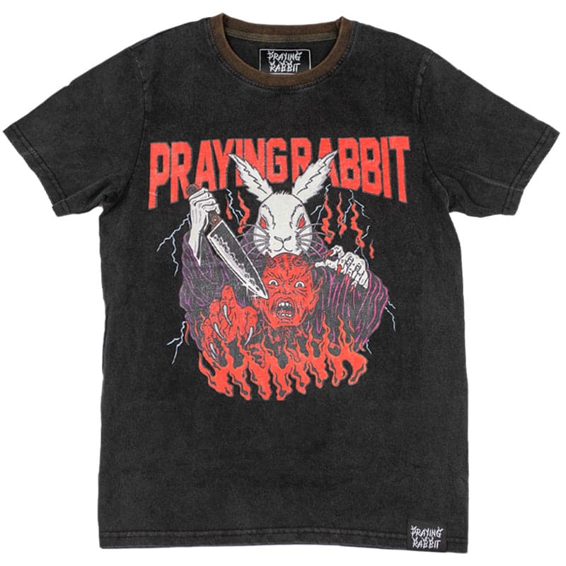 vintage washed black shirt with screen printed design of a evil white rabbit holding a knife. the white rabbit is wearing purple robes and there is a screaming demon in front of him. the rabbit is about to stab the demon. there is red text behind the characters at the top that reads praying rabbit. there is flames and lightning in the design