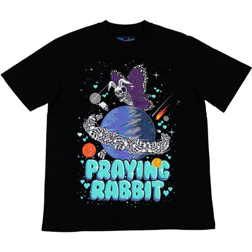 black graphic shirt with a design that shows a skeleton butterfly rabbit flying over the planet saturn. the planet saturn has skulls as rings. there is blue bubble text below the design that reads praying rabbit