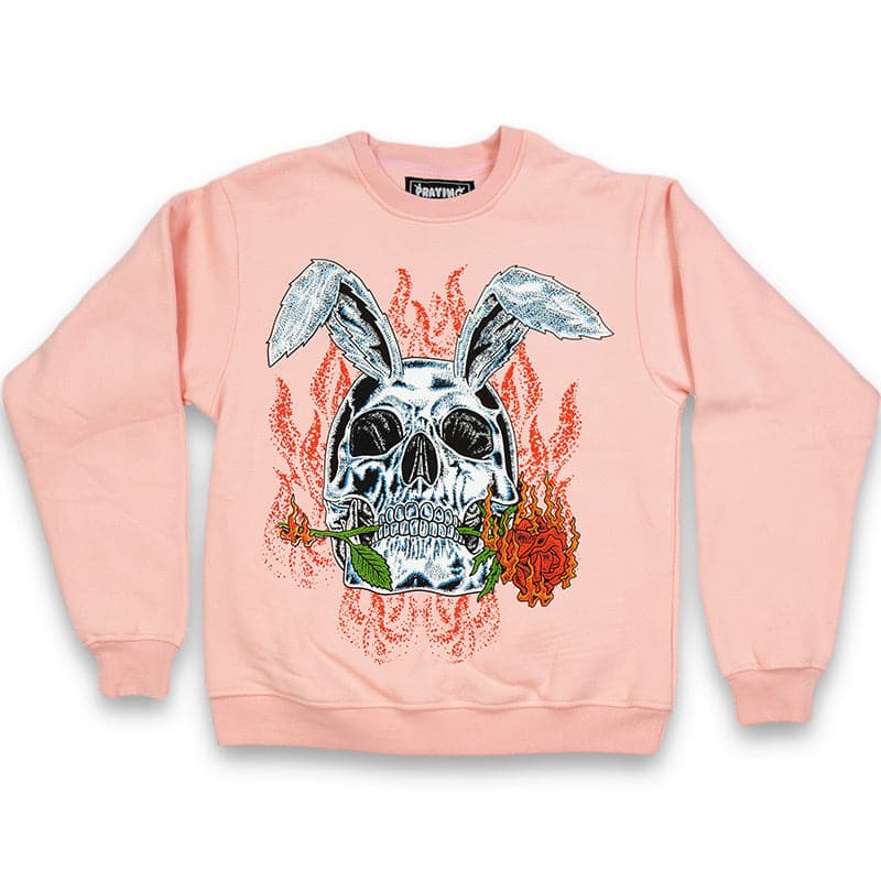 pink crew neck sweater with a printed graphic design of a rabbit skull biting a red rose with flames in the background