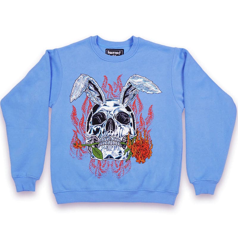 sky blue crew neck with a printed graphic design of a rabbit skull biting a red rose with flames in the background
