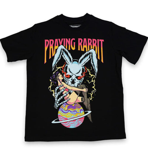 black t shirt with screen printed design of blue rabbit skeleton holding saturn planet. there is a girl sitting on top of the saturn planet and text that reads praying rabbit