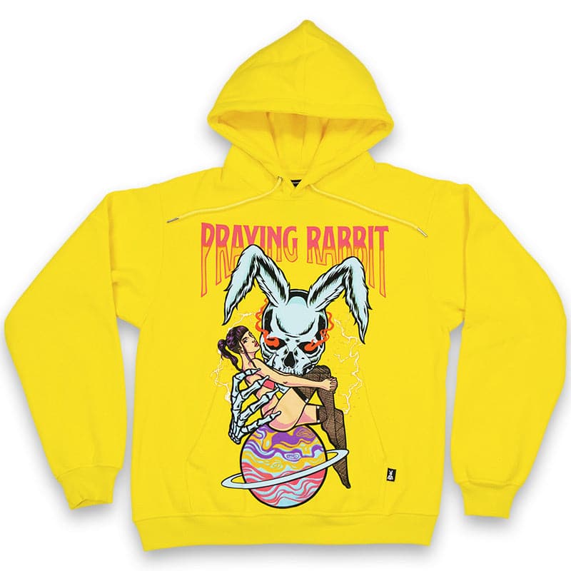 Yellow hoodie with a large over the pocket screen printed design of a blue rabbit skeleton with evil red glowing eyes. The rabbit is reaching out with one hand toward the girl who is  in front of the rabbit sitting on top of the planet saturn