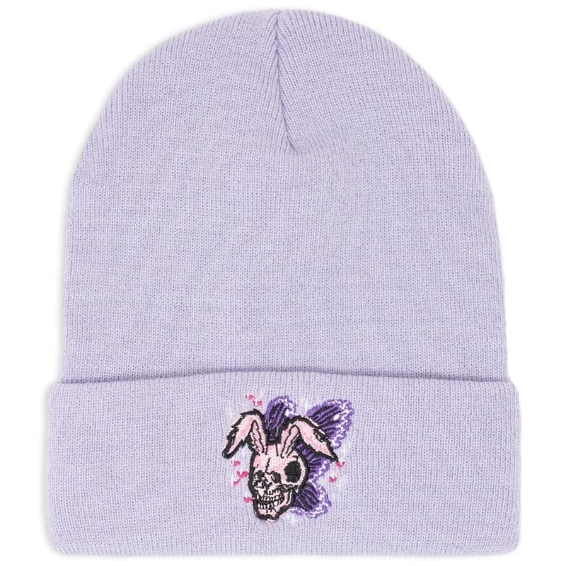 a skull the shape of a rabbit with butterfly wings embroidered on a lavender beanie. the rabbit skull has little hearts and sparkles around it