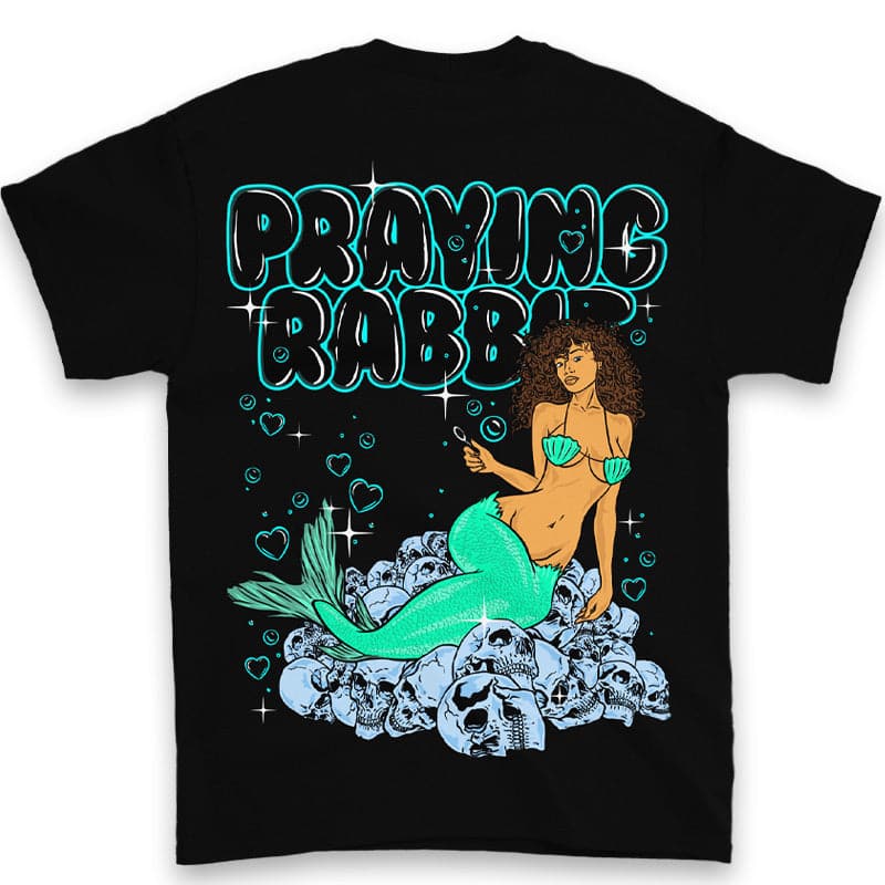 back view of black t shirt with large printed design that reads praying rabbit. below the praying rabbit text is a mermaid sitting on top of skulls. she is blowing heart-shaped bubbles