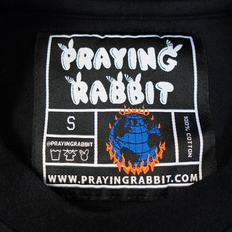 woven label that reads praying rabbit and shows the earth on fire