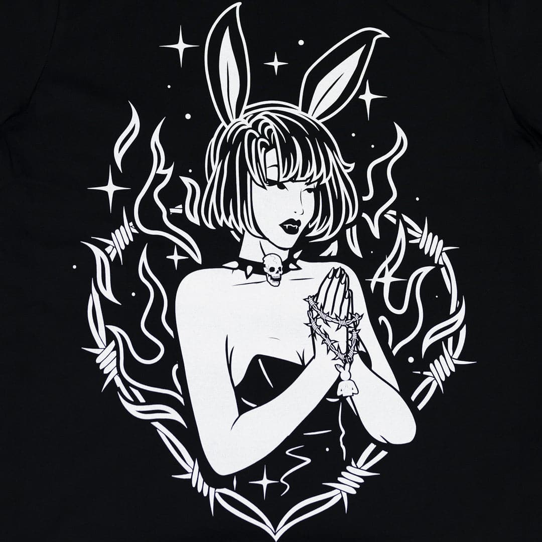 black and white design of a girl with bunny ears praying. she is inside a barb wire heart