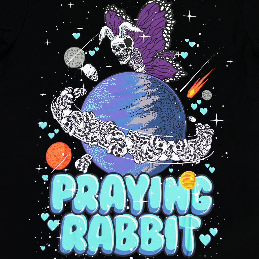 rabbit skeleton butterfly flying over saturn with skullls as the rings. there are hearts and comets around the design with text that reads praying rabbit