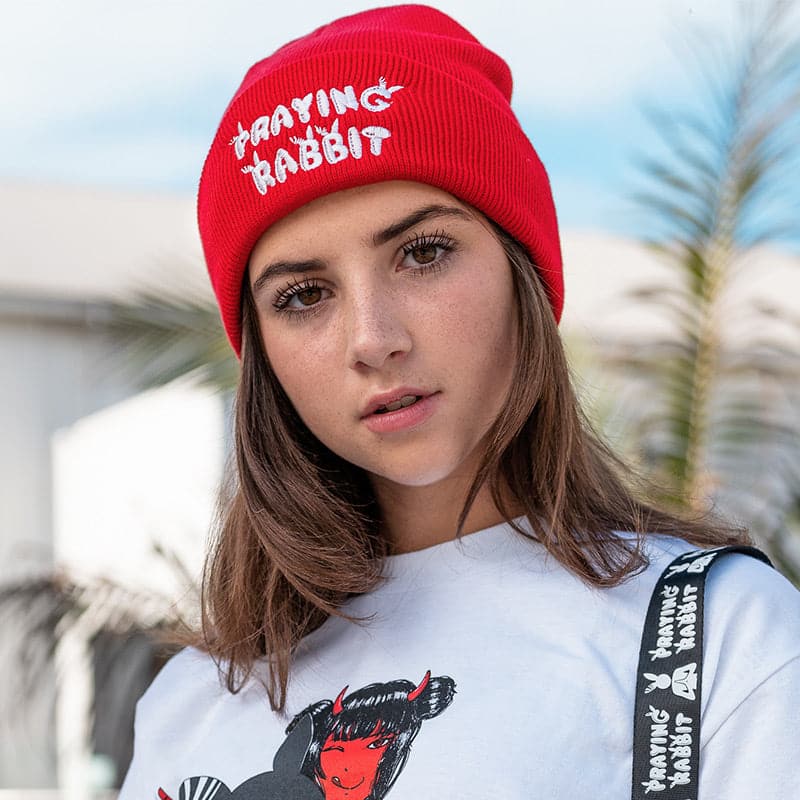 model lily spinner wearing red beanie with white praying rabbit embroidered letters