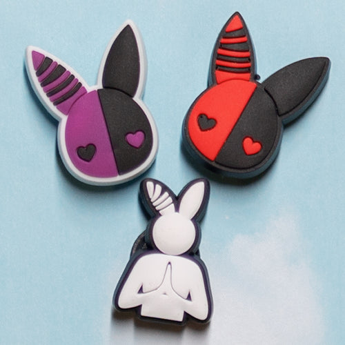 3 rabbit charms. one charm is a purple and black rabbit head with heart eyes. there's a second charm exactly the same, except in red and black. the third charm is a white and black praying rabbit