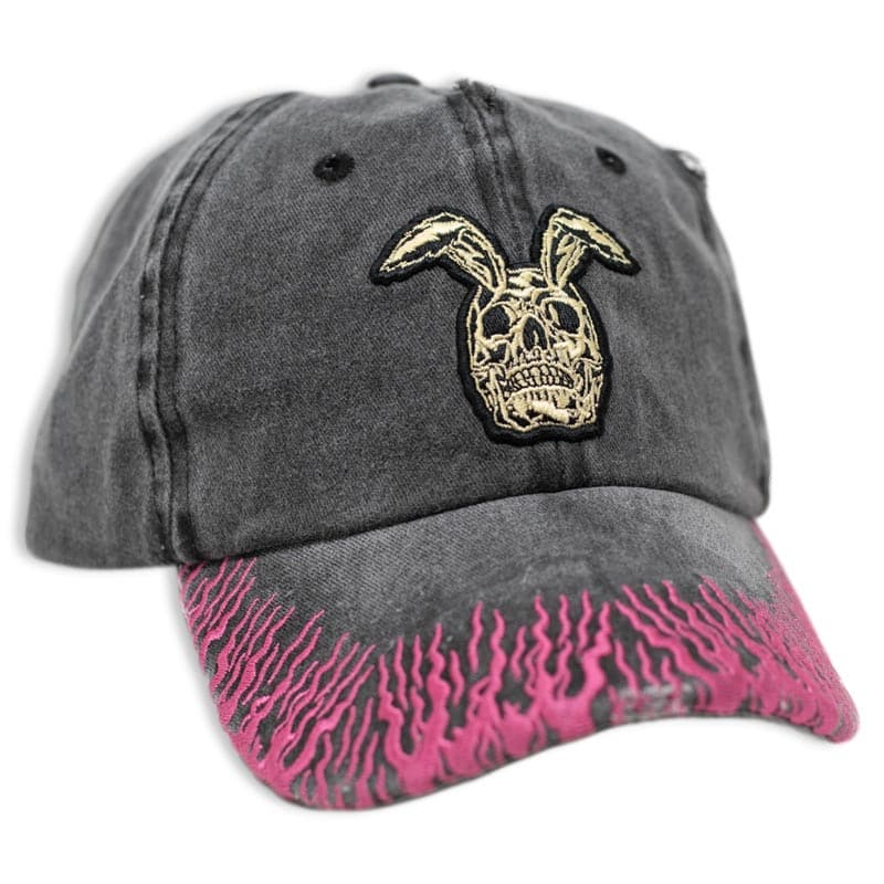 black vintage washed hat with an embroidered rabbit skull design. the brim has pink embroidered flames